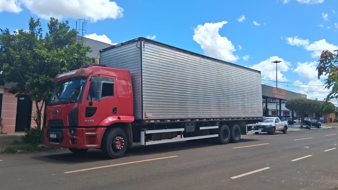Caminhão baú vermelho carregando na rua